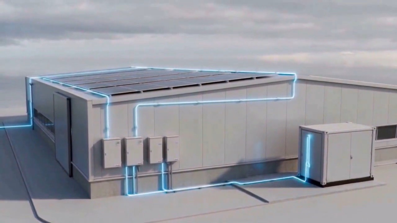 A commercial rooftop with a solar array, wired through to a battery unit beside the building